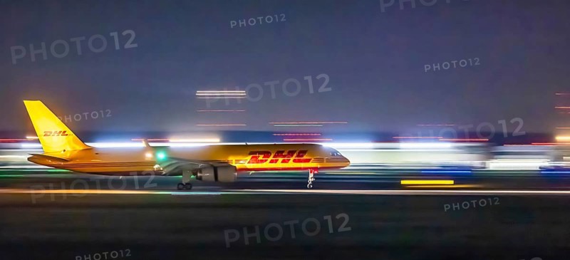 Stuttgart Airport in the early morning. DHL cargo plane landing. Light traces with motion blur. Stuttgart, Baden-Württemberg, Germany
