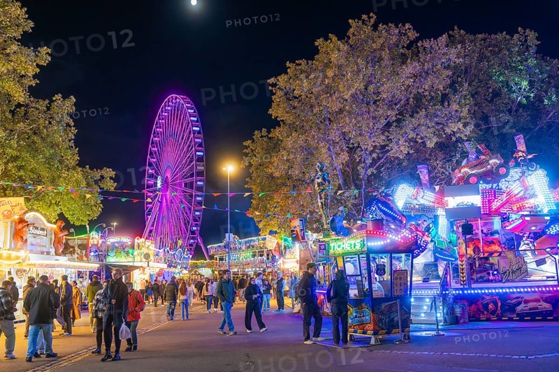 Lively night shot with illuminated Ferris wheel and colourful festival stands, Cannstatter Wasen folk festival, Stuttgart, Germany