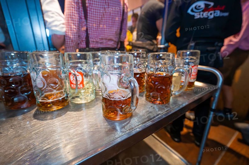 Row of beer mugs on a long wooden table at a festive event with people in the background, Cannstatter Wasen folk festival, Stuttgart, Germany