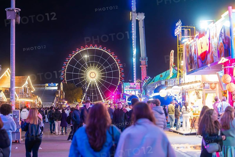 Lively funfair at night with lots of people and a large, illuminated Ferris wheel, Cannstatter Wasen funfair, Stuttgart, Germany