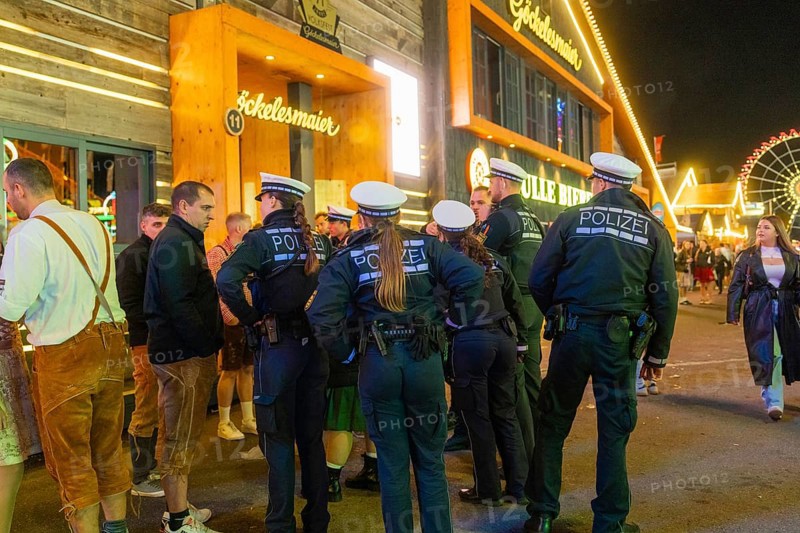 Police officers monitor the marquee area at night and ensure safety among the visitors, Cannstatter Wasen folk festival, Stuttgart, Germany