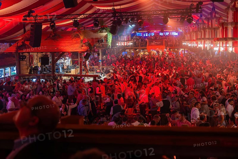 A well-attended marquee with red lights and a cheerful party atmosphere, Cannstatter Wasen folk festival, Stuttgart, Germany