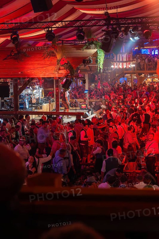 Crowded hustle and bustle in an atmospherically illuminated beer tent at the festival, Cannstatter Wasen folk festival, Stuttgart, Germany