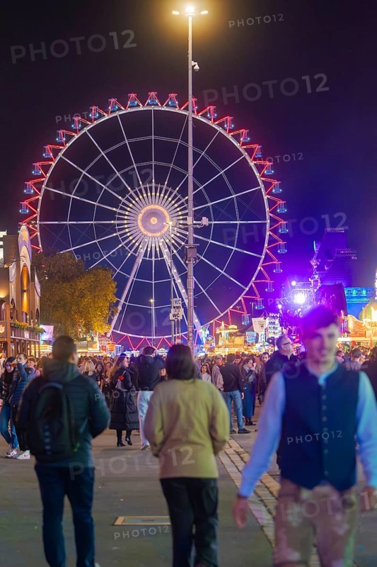 Large Ferris wheel at night, surrounded by a lively crowd, Cannstatter Wasen folk festival, Stuttgart, Germany
