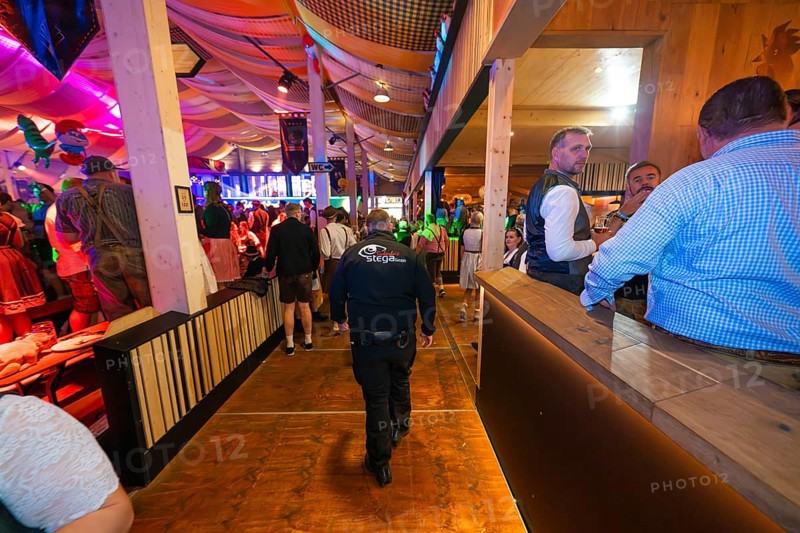 Security guard in a well-filled marquee with atmospheric lighting, Cannstatter Wasen folk festival, Stuttgart, Germany