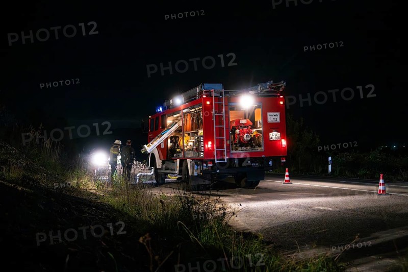 Fire engine with bright lights standing on a road at night, surrounded by traffic cones, fire brigade exercise in the new construction tunnel of the Hermann Hesse railway, Ostelsheim, Calw district, Germany