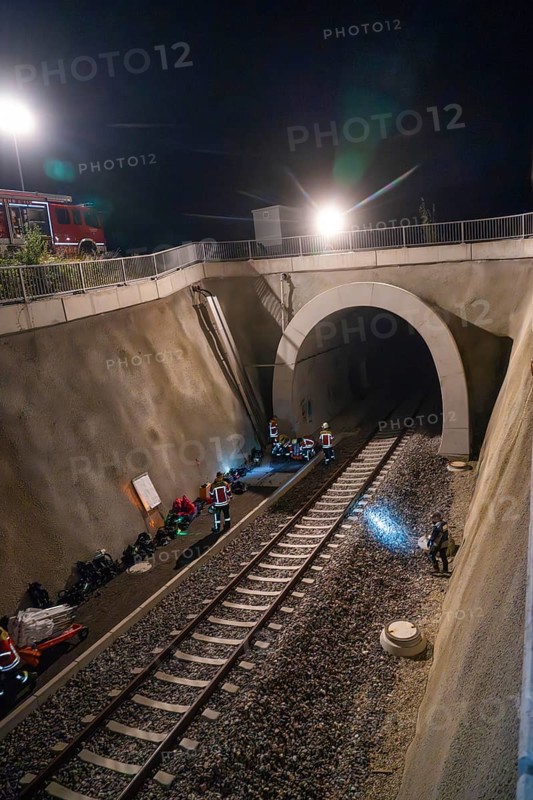 Rescue workers working in an illuminated tunnel at night, railway tracks in the foreground, fire brigade exercise in the new tunnel of the Hermann Hessebahn, Ostelsheim, district of Calw, Germany