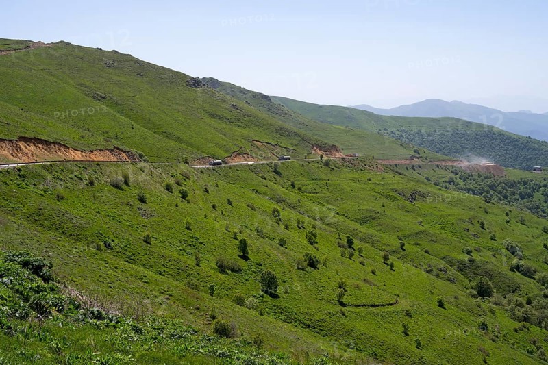 Road runs along the green hills in a landscape with mountains, at the highest pass in Armenia, Meghri Pass, Tashtun Pass, Syunik Province, Syunik, Armenia