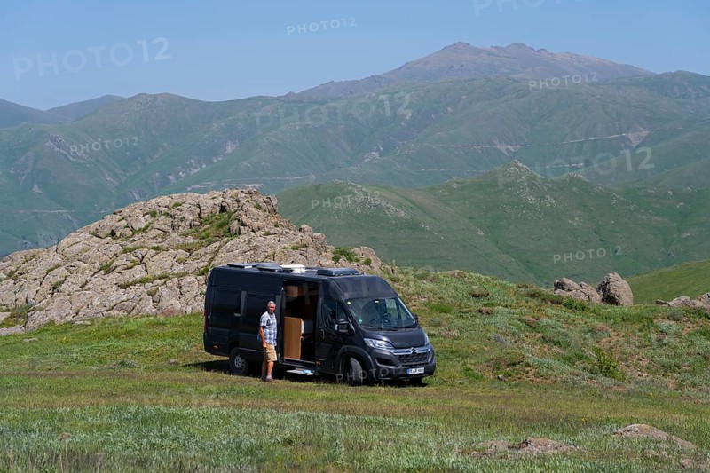 Man next to a camper in a green, mountainous landscape, camper at the highest pass of Armenia, Meghri Pass, Tashtun Pass, Syunik Province, Syunik, Armenia