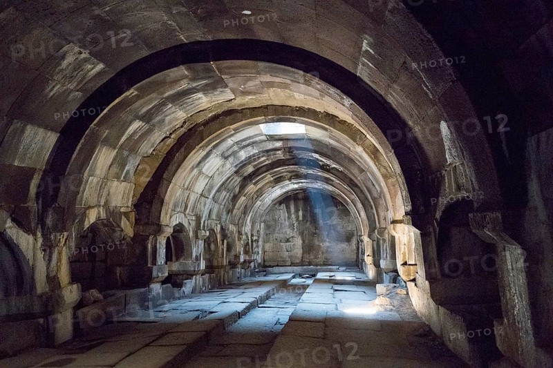 Interior view of an ancient vault with stone arches and a beam of light creating a mysterious atmosphere, Orbelian's Caravanserai, Selim Caravanserai, located at the Vardenyats Pass or Selim Pass, Vayots Dzor Province, Armenia