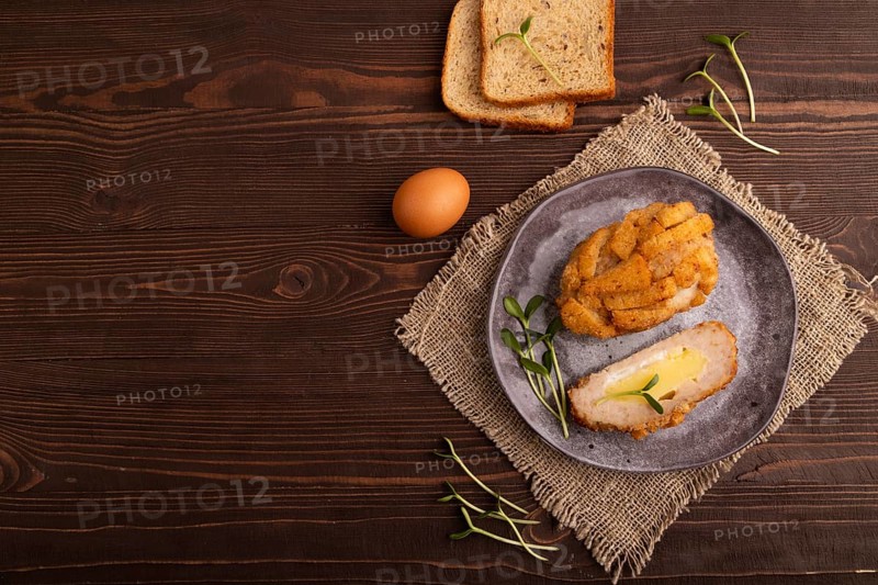 Chicken Schnitzel on gray plate with microgreen on brown wooden background and linen textile. top view, flat lay, copy space