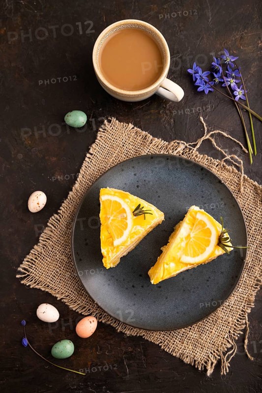Lemon cake on black concrete background and linen textile, cup of coffee, top view, flat lay, close up