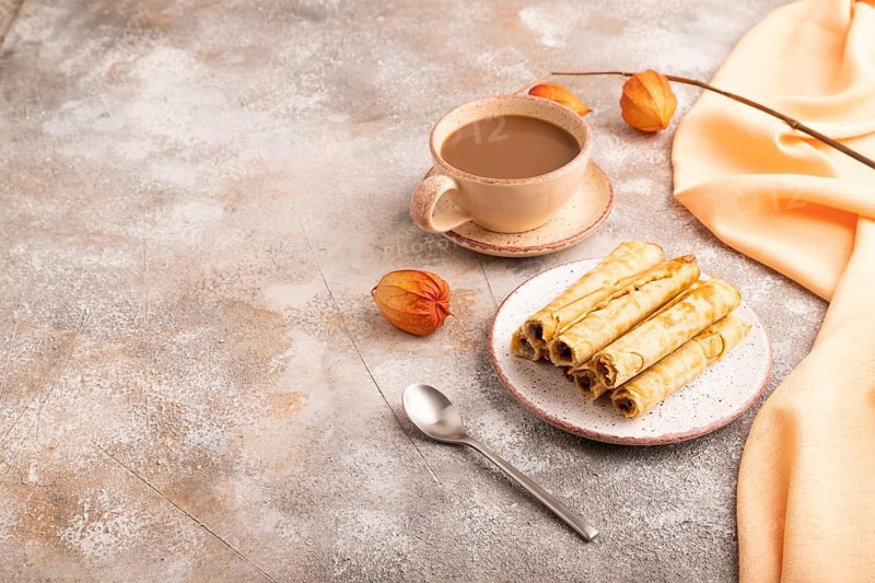 Waffles with caramel on brown concrete background and orange linen textile, cup of coffee, side view, copy space