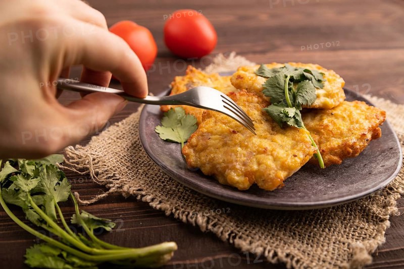 Fried crispy Chicken pancakes with hand on brown wooden background and linen textile. side view, close up, selective focus