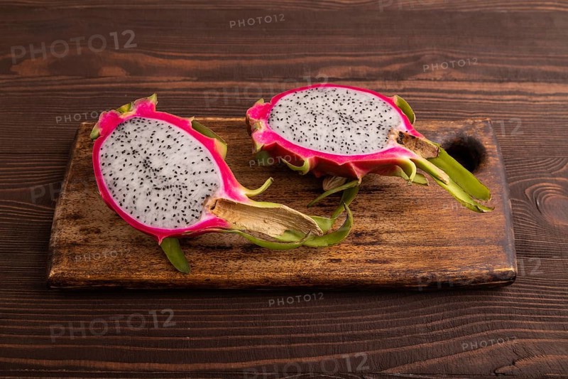 Ripe Pitaya on cutting board on brown wooden background, side view, copy space, minimalism