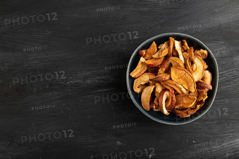 Dried Apples in ceramic bowl on black wooden background. Top view, copy space, flat lay. healthy food, minimalism. sweet