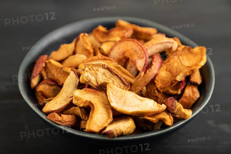 Dried Apples in ceramic bowl on black wooden background. Side view, close up. healthy food, minimalism. sweet, selective focus