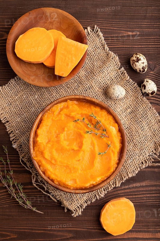 Sweet potato porridge in wooden bowl on wooden background and linen textile. Diet, healthy eating concept. top view, flat lay, close up, minimalism