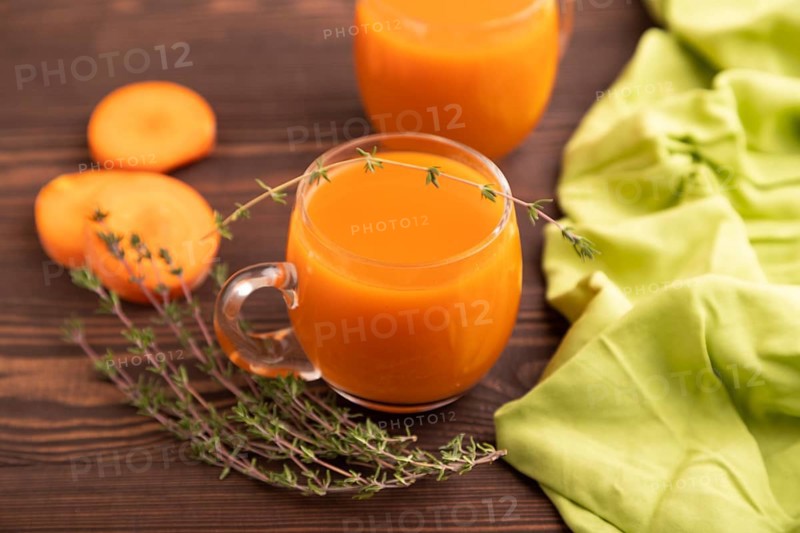 Two glasses with carrot juice, on wooden background and green textile. Diet, healthy eating concept. side view, close up, minimalism, selective focus
