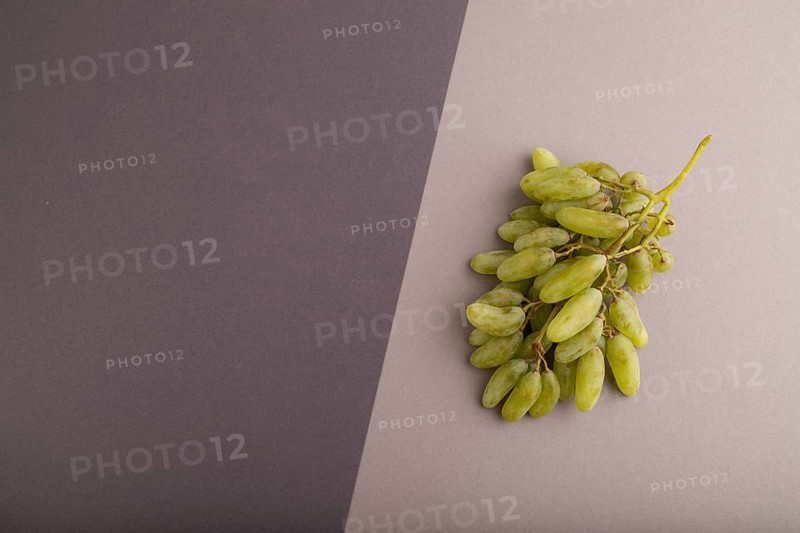 Green grapes on gray and black paper pastel background. Top view, flat lay, copy space. healthy food, minimalism