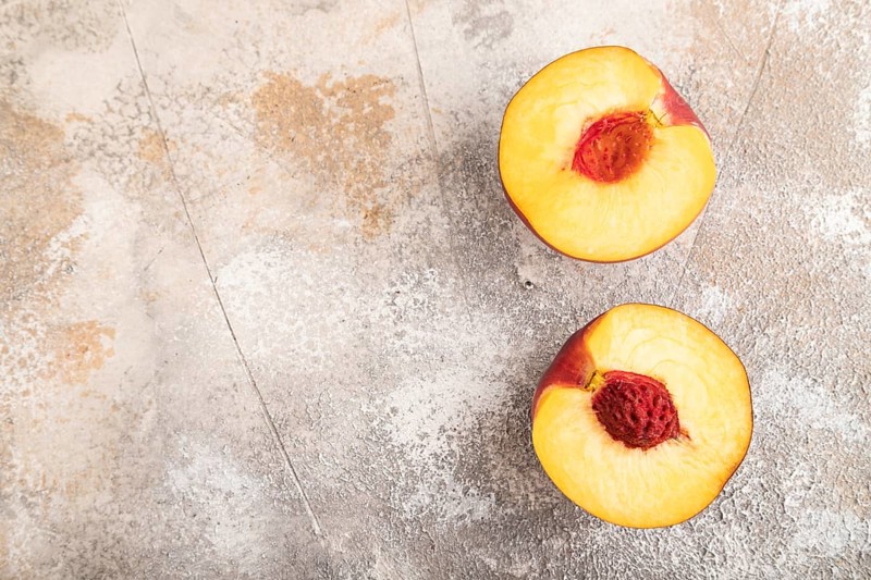 Peach Cut in half on brown concrete background. Top view, flat lay, copy space. healthy food, vegetable, minimalism