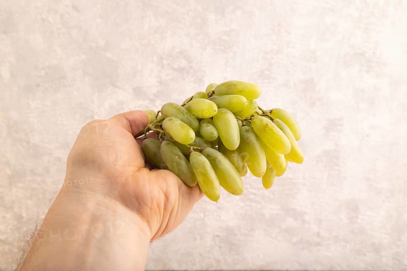 Green grapes on gray concrete background. Side view, copy space. healthy food, minimalism