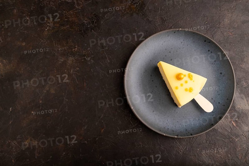 Yellow Cake pop with sprinkles on blue ceramic plate on black concrete background, top view, flat lay, copy space, minimalism