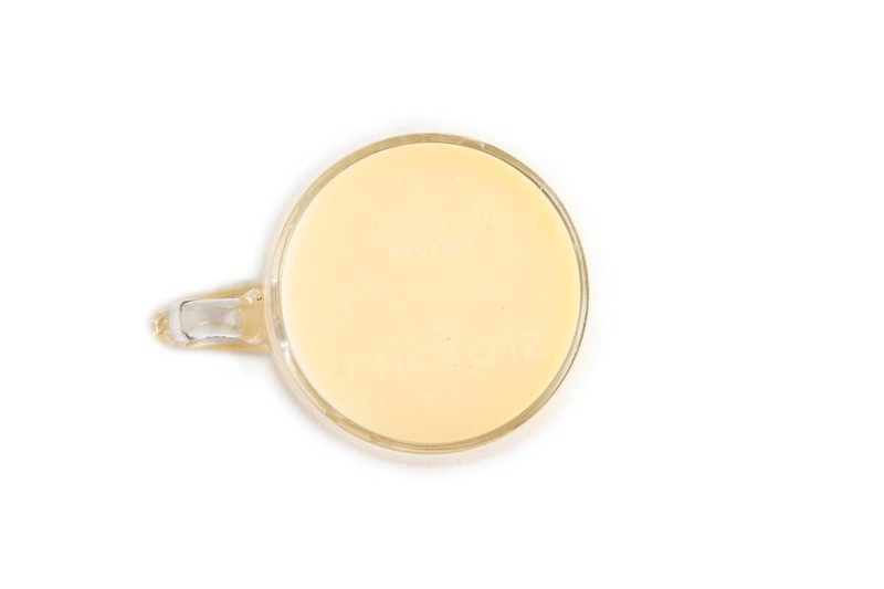 Organic non dairy banana and soy milk in glass isolated on white background. Vegan healthy food concept, flat lay, top view, close up