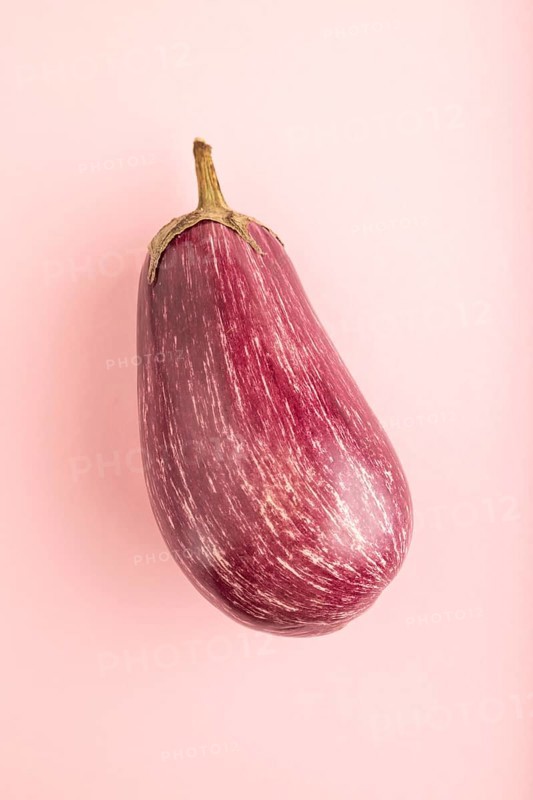 Purple eggplant with white stripes on pink pastel background. Top view, flat lay, copy space. Tropical, healthy food, vegetable, minimalism