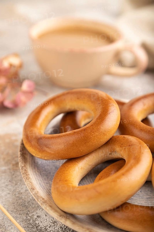 Homemade Ring Bagel with cup of coffee on brown concrete background and linen textile. side view, close up, selective focus
