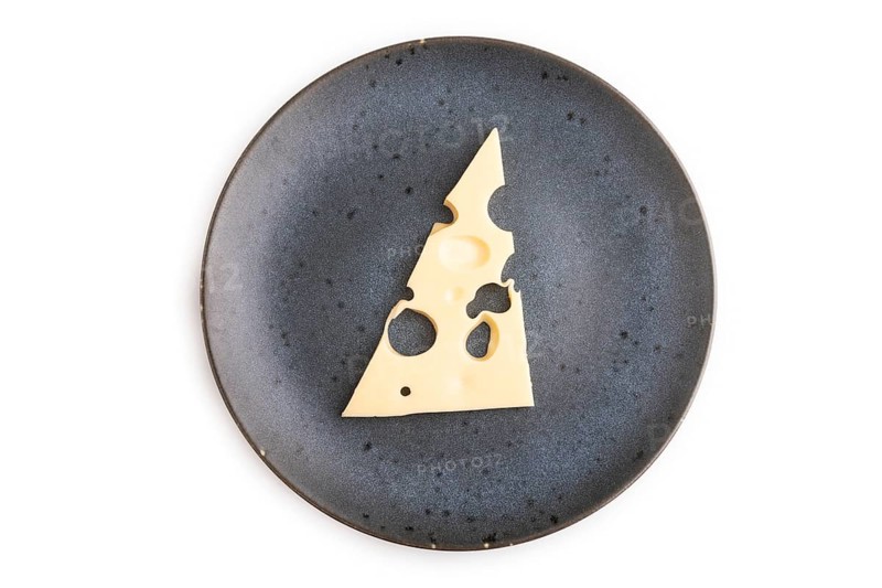 Piece of cheese with holes on blue plate isolated on white background, top view, flat lay, copy space, minimalism