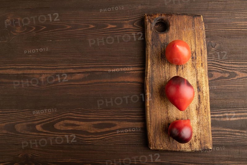 Yellow tomatoes on cutting board on brown wooden background. Top view, copy space, flat lay. healthy food, vegetable, minimalism
