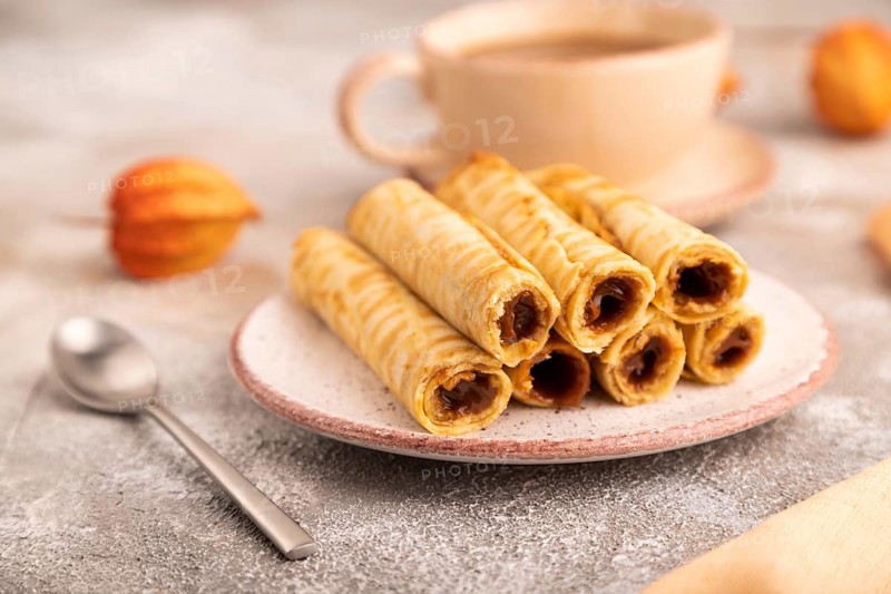 Waffles with caramel on brown concrete background and orange linen textile, cup of coffee, side view, close up, selective focus