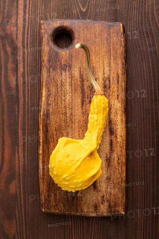 Decorative orange Pumpkin on cutting board on brown wooden background, top view, flat lay, close up, minimalism