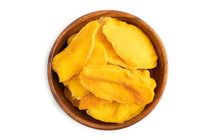 Dried Mango in wooden bowl isolated on white background. Top view, close up, flat lay. healthy food, minimalism