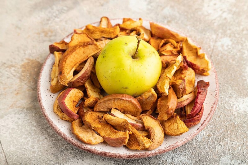 Dried Apples in ceramic bowl on brown concrete background. Side view, copy space, flat lay. healthy food, minimalism. sweet