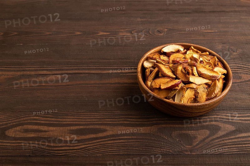Dried Apples in wooden bowl on brown wooden background. Side view, copy space, healthy food, minimalism. sweet