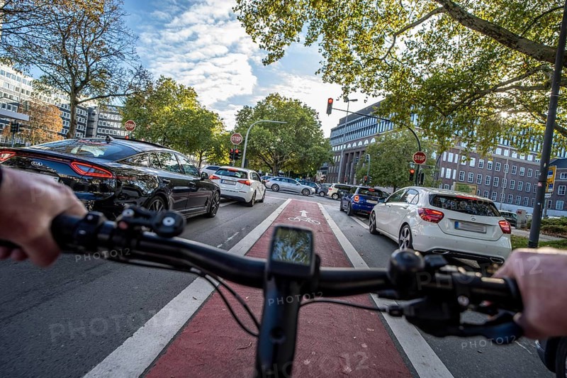 Riding a bike in a bike lane, marked in red to make drivers aware of the bike lane, between 2 lanes, Huyssenallee, in the city centre of Essen, North Rhine-Westphalia, Germany