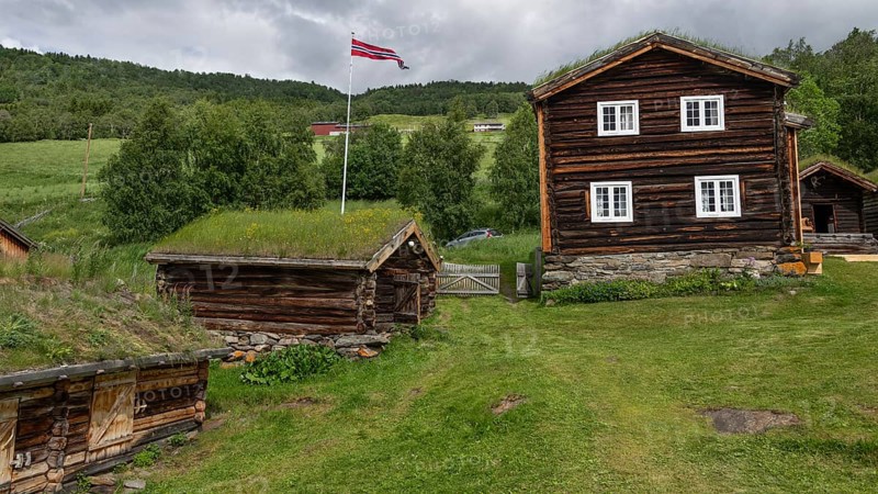 Norwegische Holzhäuser mit Gras auf den Dächern, Fahnenmast mit Norwegen-Flagge, historischer Bauernhof und Pilgerunterkunft Budsjord, Dovre, Pilgerweg Olavsweg oder Olavsleden, Gudbrandsdalen oder Gudbrandstal, Norwegen