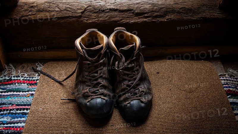 Eingetragene Wanderschuhe auf einem Teppich in einem rustikalen Innenraum, historischer Bauernhof und Pilgerunterkunft Budsjord, Dovre, Pilgerweg Olavsweg oder Olavsleden, Gudbrandsdalen oder Gudbrandstal, Norwegen