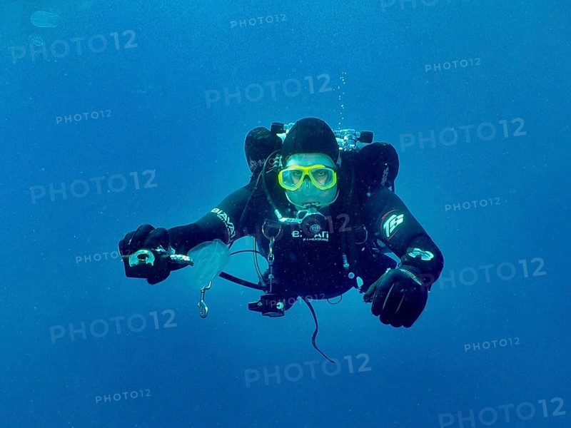 Ein Taucher mit kompletter Tauchausrüstung streckt seinem Tauchpartner, dem offenbar die Luft ausgegangen ist, den zweiten Regler hin, um seine Luft zu teilen. Tauchplatz Wrack der Vis, Pula, Kroatien, Mittelmeer