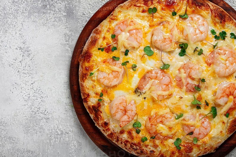 Four cheese pizza with shrimp and fresh microgreens, served on a wooden board, homemade, no people