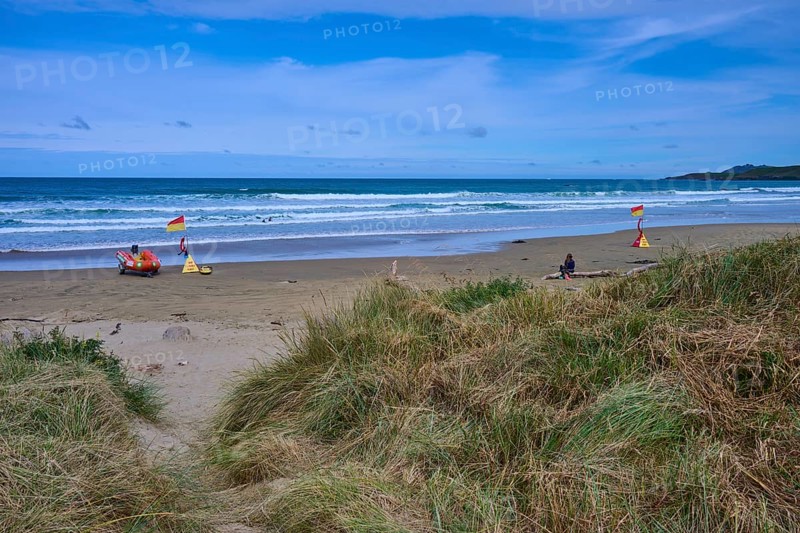 Rettungsflaggen am Strand mit grasbewachsenen Dünen und leichten Wellen im Meer, Kaka Point, Clutha District, Otago, Südinsel, Neuseeland