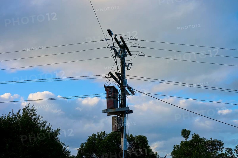 Ein Strommast mit Kabeln unter einem teils bewölkten, sonnigen Himmel, Moeraki, Hampden, North Otago, Südinsel, Neuseeland