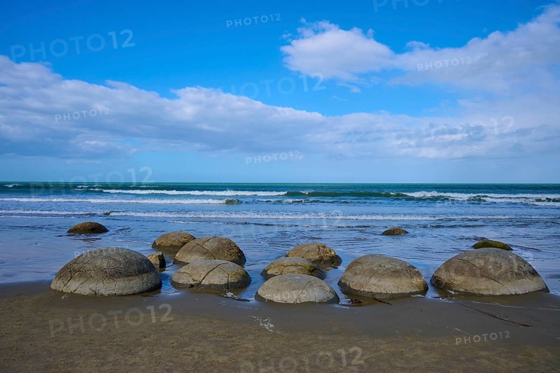 Runde Felsen verteilen sich am Strand unter einem blauen Himmel mit Wolken, Moeraki Boulders, Moeraki, Hampden, North Otago, Südinsel, Neuseeland