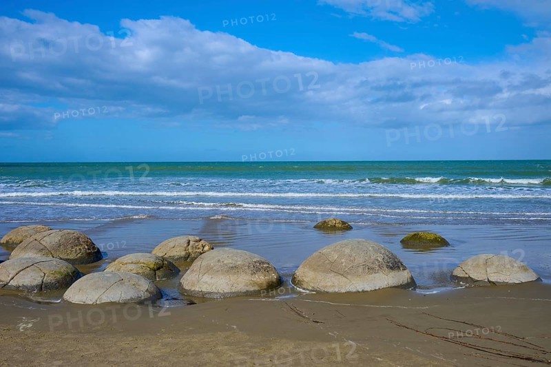 Mehrere runde Felsen an einem Sandstrand mit Blick auf das Meer und bewölkten Himmel, Moeraki Boulders, Moeraki, Hampden, North Otago, Südinsel, Neuseeland