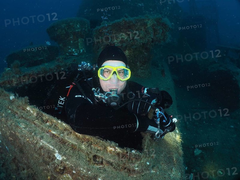 Diver looking out of the hatch of a wreck. Dive site wreck of the Vis, Pula, Croatia, Mediterranean Sea
