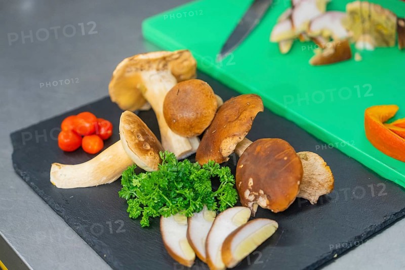 Various mushrooms and herbs on a black plate