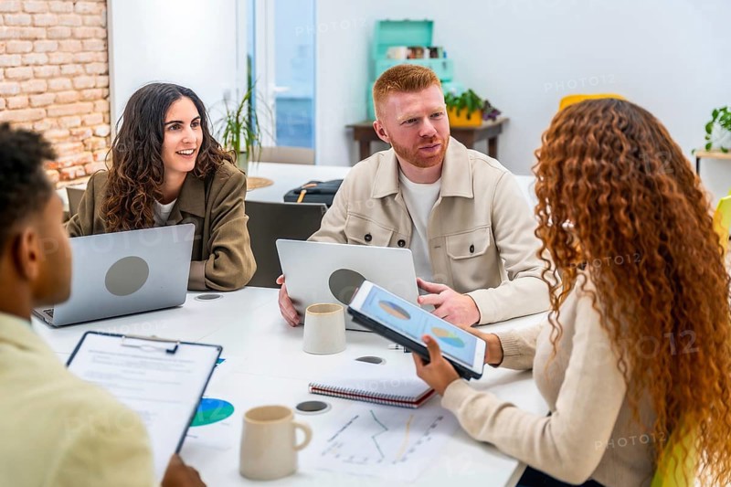 Diverse business people sharing ideas and analyzing data during a dynamic team meeting, discussing market insights and growth strategies in a modern office environment