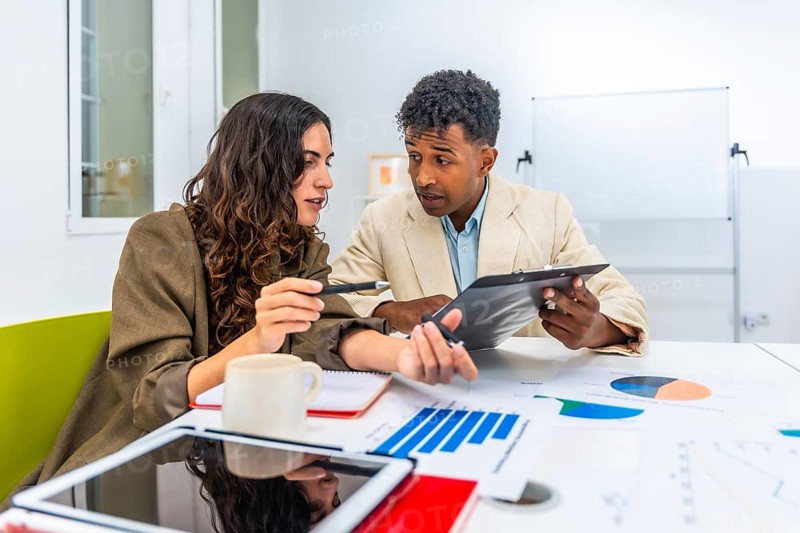 Diverse business colleagues discussing financial data and charts during an office meeting, collaborating on a project and analyzing performance figures for strategy development